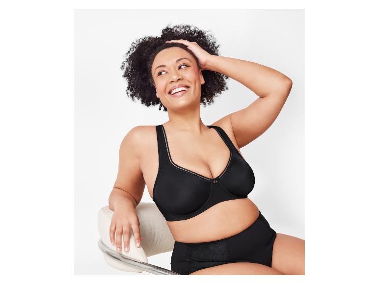 Een vrouw lacht terwijl ze een zwarte Elomi Cate beugel bh en een hoge taille slip draagt.