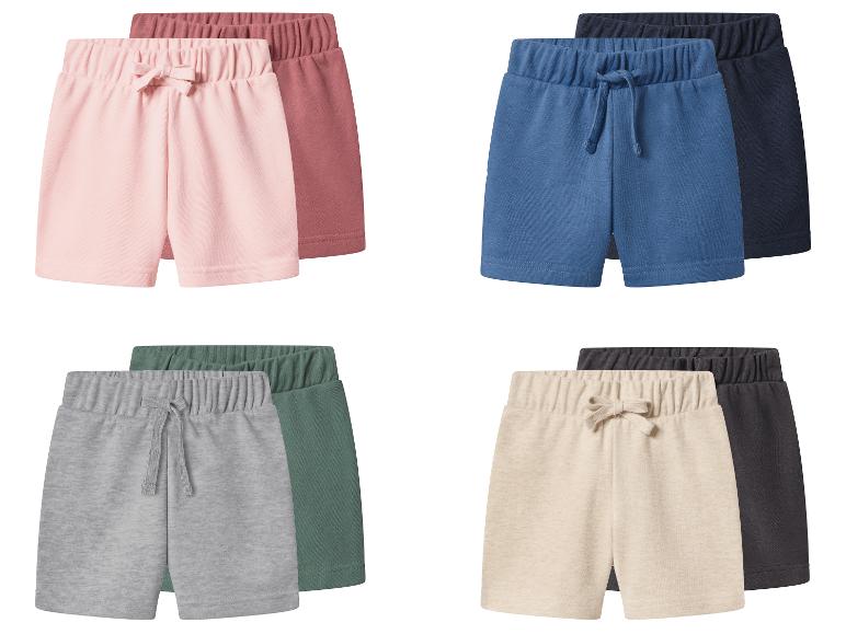Vier paar kinderbroekjes in roze, blauw, grijs en beige, elk met een donkerdere complementaire kleur.