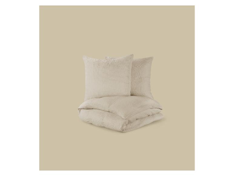 Lichtbeige beddengoedset met twee kussens en een opgevouwen dekbed.