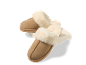 Paar comfortabele beige suède pantoffels met crèmekleurige imitatiebont voering, rustend op een wit blok.