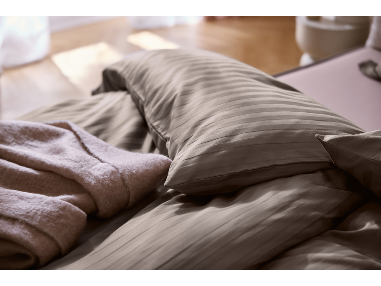 Gestreept beddengoed en een zachte deken in een slaapkamer.