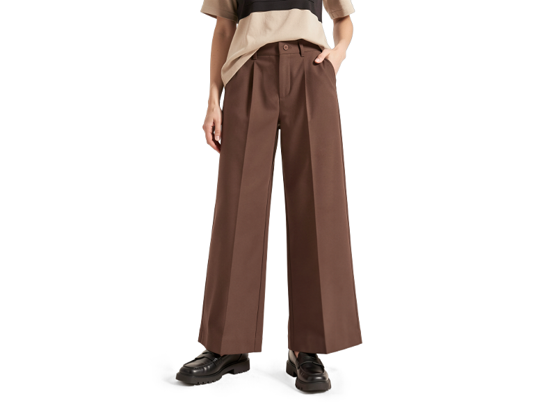 Vrouw draagt bruine wijde broek met plooien en een gestreept T-shirt, gecombineerd met zwarte loafers.
