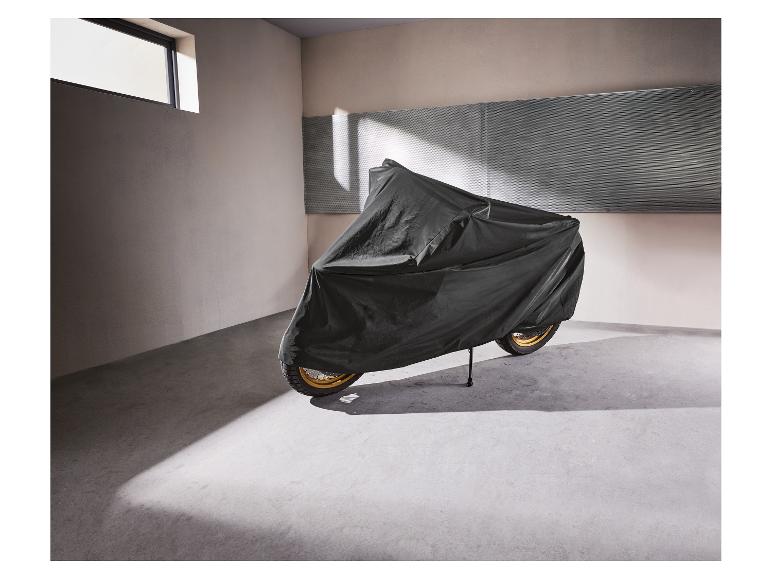 Motorfiets bedekt met een zwarte beschermhoes in een garage.