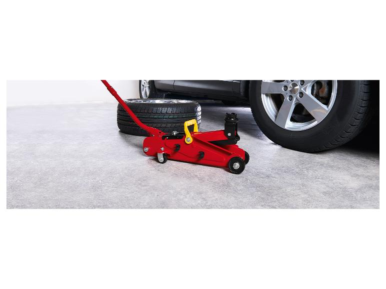 Rode autokrik en band naast een auto in een garage.
