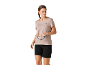 Vrouw in beige sportshirt en zwarte shorts, houdt zonnebril vast.