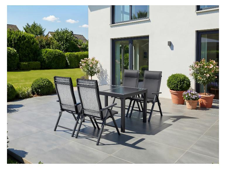 Tuinmeubelset op het terras: tafel en vier stoelen, omringd door groen.