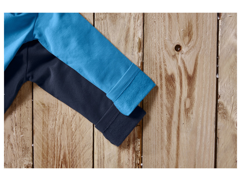 Blauwe en donkerblauwe mouwen van een trui op een houten achtergrond.