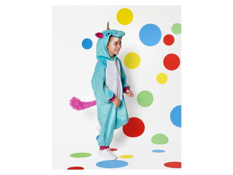 Een kind in een eenhoornkostuum staat voor een muur met gekleurde cirkels.