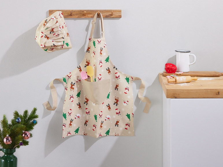 Een kerst-schort met rendieren en kerstmannen, een bijpassende kerst-kokmuts en keukengerei.