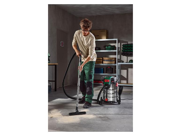 Man stofzuigt een garagevloer met een Parkside nat- en droogzuiger.