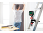 Laserwaterpas bevestigd aan een ladder, met een persoon die behangt op de achtergrond.