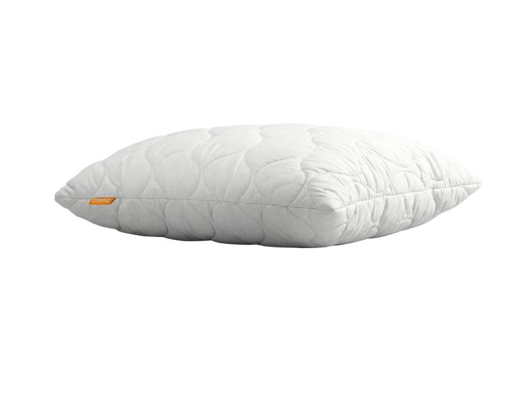 Wit gewatteerd kussen met een golfpatroon, liggend op een witte achtergrond.