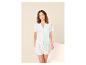 Vrouw in witte broderie anglaise pyjama, met een shirt met korte mouwen en een short.