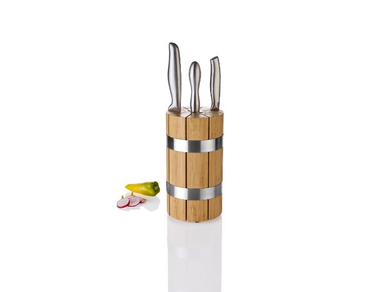 Keukenmessen in een houten standaard met kookingrediënten.