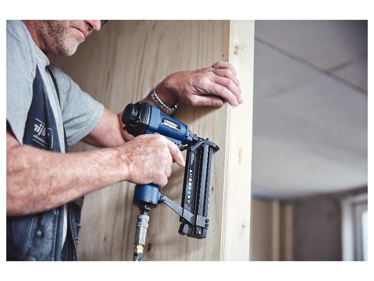 Man gebruikt een pneumatische tacker/spijkerpistool om houten panelen te bevestigen.