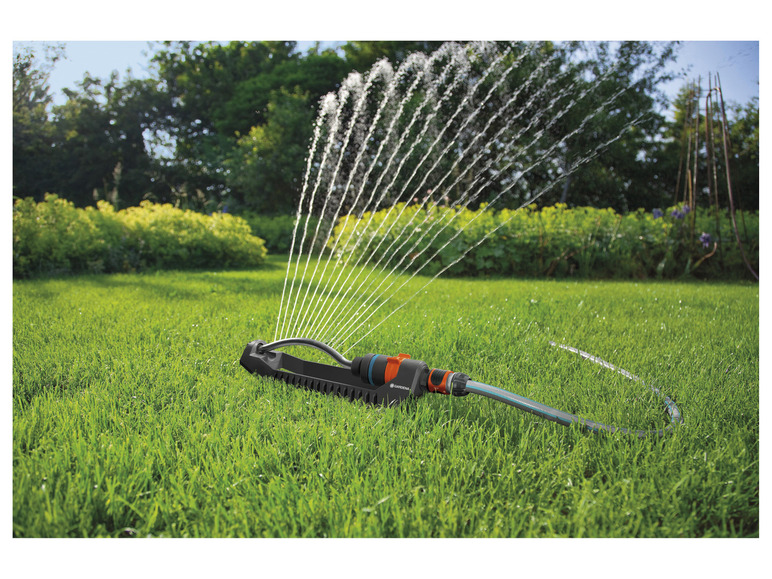 Een Gardena sproeier besproeit een gazon met water.