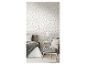 Slaapkamer met bloemenbehang, bed met grijs beddengoed en een pied-de-poule fauteuil.