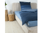 Slaapkamer met blauw gestreept beddengoed, lichtblauw hoeslaken en twee houten bijzettafels.