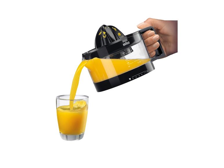 Hand schenkt vers geperst sinaasappelsap uit een citruspers in een glas.