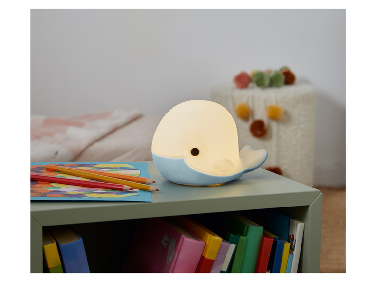 Een blauwe walvis nachtlamp op een groene nachtkastje.