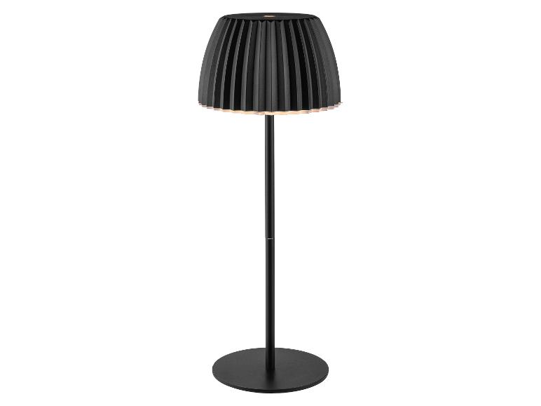 Zwarte vloerlamp met geplooide kap, die een warme gloed afgeeft.