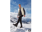 Man in gewatteerd vest en trui, broek en wandelschoenen in de sneeuw.