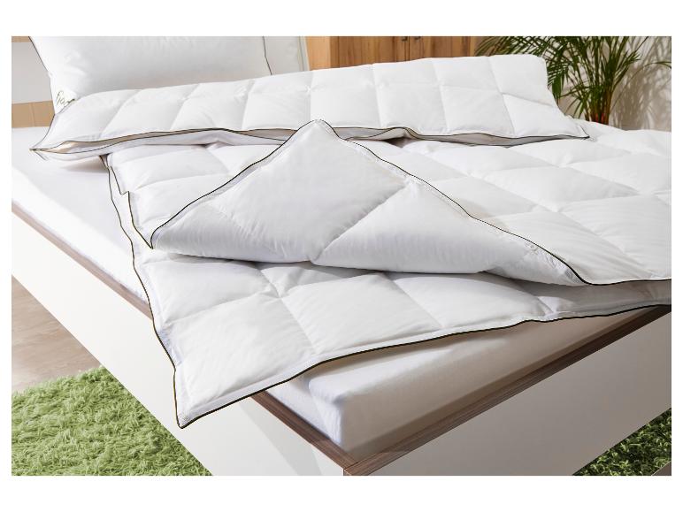 Wit dekbed en kussen met donkere bies op een bed met groen vloerkleed