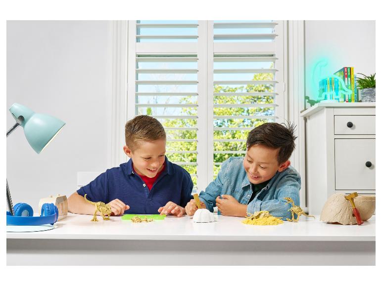 Twee jongens spelen met dinosaurus opgravingskits en dinosaurusskeletten.