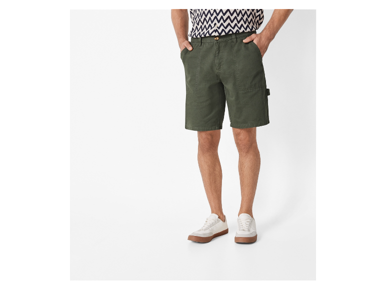 Olijfgroene werkshorts en witte sneakers.