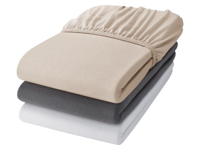 Gestapelde hoeslakens in beige, grijs en wit.