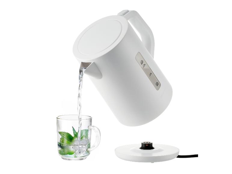 Witte waterkoker schenkt water in een glas met munt en ijs.