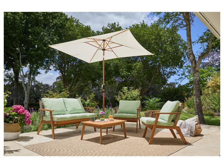 Buiten loungeset met houten meubels, groene kussens, een beige parasol en een geweven vloerkleed.