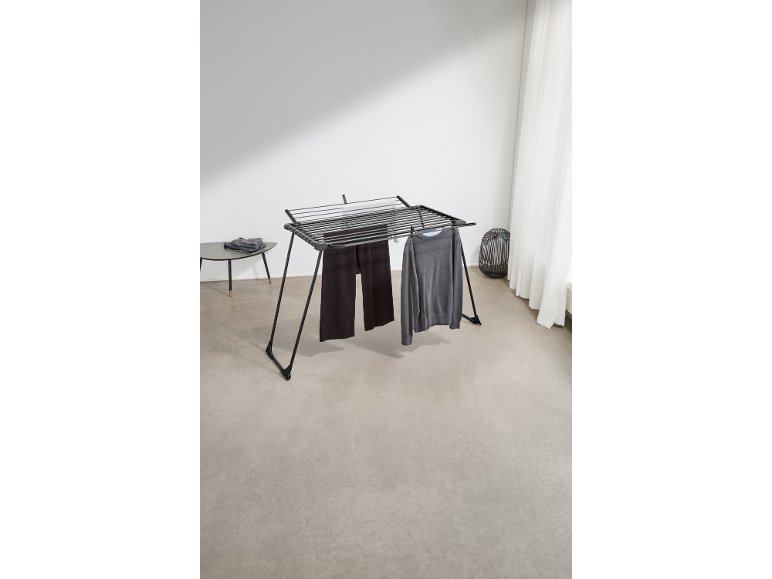 Zwart wasrek met een grijze trui en donkere broek, in een lichte kamer.
