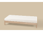 Lichte houten bank met wit kussen op een beige achtergrond.