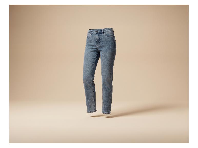 Blauwe gewassen damesjeans, zwevend op een beige achtergrond.