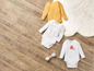 Baby onesies met printjes en een gele romper.