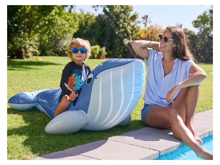 Kind op een opblaasbare walvis bij een zwembad.