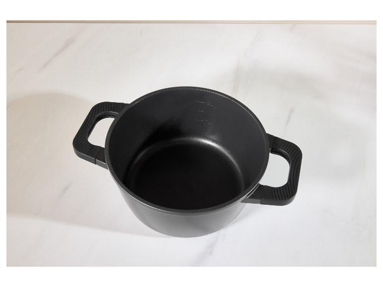 Zwarte pan met twee handvatten en maatstreepjes op een wit marmeren oppervlak