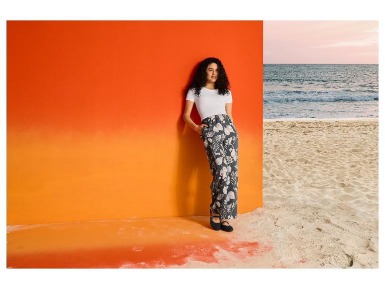 Vrouw in ESMARA® T-shirt-body en broek met print bij het strand.