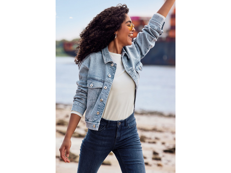 Een vrouw draagt een spijkerjack en spijkerbroek.