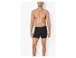 Man met ontbloot bovenlichaam, draagt zwarte boxershort, tegen een witte achtergrond.
