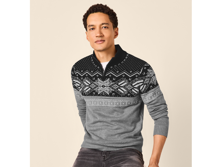 Man in een grijs en zwart Fair Isle patroon half-zip trui en donkere jeans.