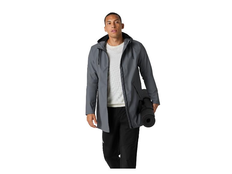 Man in grijze jas en zwarte broek, met opgerolde yogamat.
