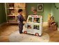 Kinderen spelen met een houten speelgoedfoodtruck in een feestelijk versierde kamer.