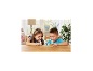 Twee lachende kinderen spelen met dierenfiguren aan een houten tafel.
