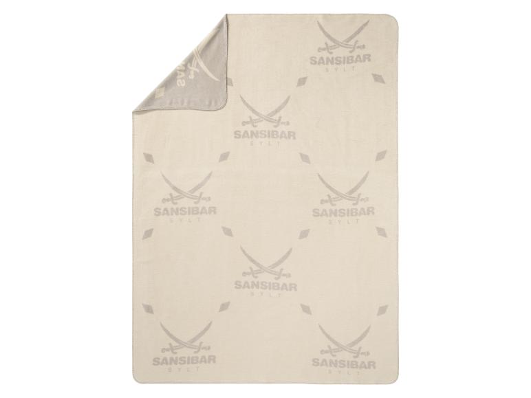 Een beige deken met het logo van Sansibar Sylt.