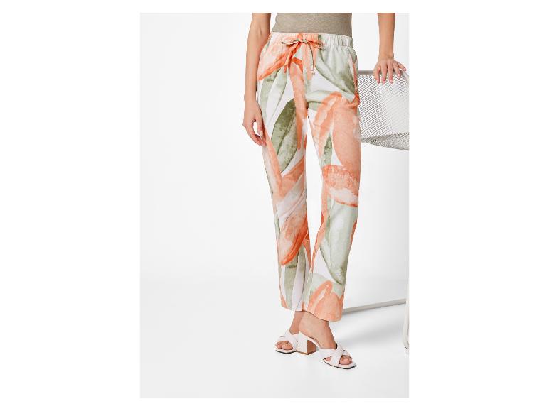 Vloeiende broek met bloemenprint en witte mules.