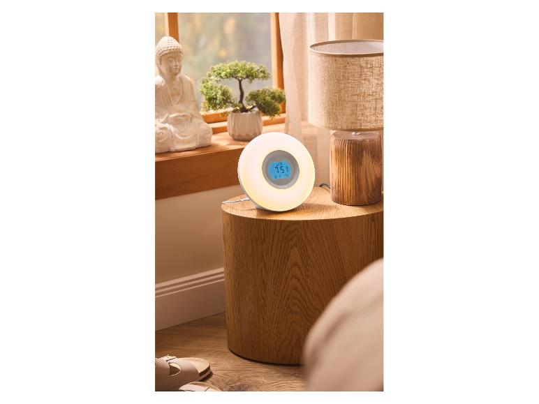 Lichtwekker op nachtkastje met lamp en decoratie, raam op de achtergrond.