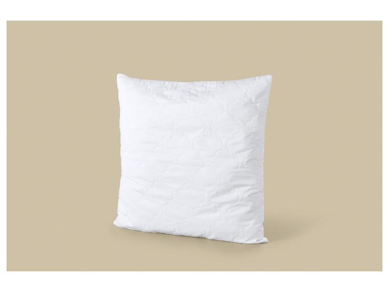 Wit gewatteerd kussen op een beige achtergrond.