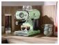 Mintgroen koffiezetapparaat met twee kopjes espresso op een houten aanrecht.